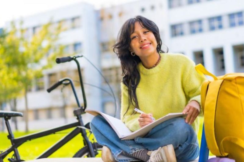 female smiling to camera looking at a book